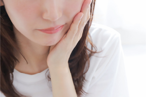 口を気にする女性の写真